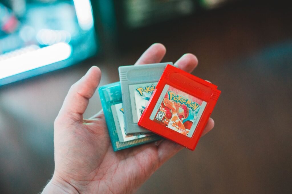 Hand holding vintage Pokemon game cartridges, showcasing nostalgic gaming.