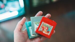 Hand holding vintage Pokemon game cartridges, showcasing nostalgic gaming.
